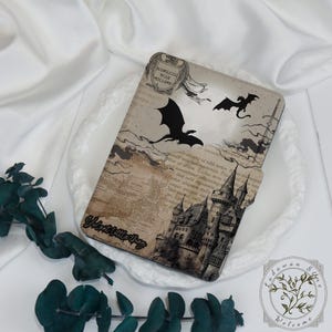 Może przedstawiać: Etui na tablet o tematyce fantasy, z zamkiem, smokami i projektem mapy w odcieniach brązu i szarości. Etui ma tekst "Valent little thing" i "Padawan Store Welcome".