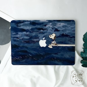 May include: Laptop cover featuring a Snoopy illustration sitting next to a white Apple logo. The background is a dark blue, textured painting of a stormy sea. Snoopy wears a blue and white jersey with the number 05 and the letter S.