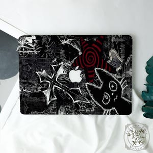 May include: Black laptop skin with a gothic design. Features a white cross, a red and black spiral, and a black cat illustration. The background is filled with white scribbles and patterns. The Apple logo is visible.