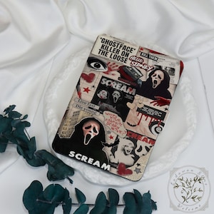 Könnte beinhalten: Eine rechteckige Handyhülle mit einer Collage aus Bildern und Text aus dem Horrorfilm "Scream". Das Design zeigt den Ghostface-Killer, das Wort "SCREAM" und andere verwandte Grafiken in Schwarz, Weiß und Rot. Die Hülle liegt auf einem weißen Teller.