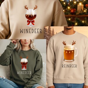 May include: A beige sweatshirt featuring a graphic of a wine glass with reindeer antlers, string lights, and a red bow, with the text Winedeer. A second beige sweatshirt shows a beer mug with antlers and lights, with the text Reinbeer.