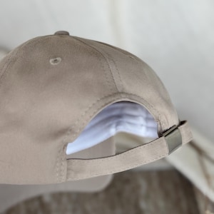 Peut inclure: Casquette de baseball beige avec une visi&egrave;re incurv&eacute;e. La casquette est dot&eacute;e d'une fermeture &agrave; boucle m&eacute;tallique et d'un petit &eacute;vent sur le dessus. La doublure int&eacute;rieure est blanche. Fabriqu&eacute;e en tissu doux et r&eacute;sistant.
