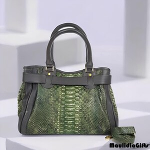 May include: A green snakeskin-patterned handbag with black leather accents, handles, and a matching small wallet. The handbag features a top handle design and a belt-like closure. The brand name "MaulidiaGifts" is visible.
