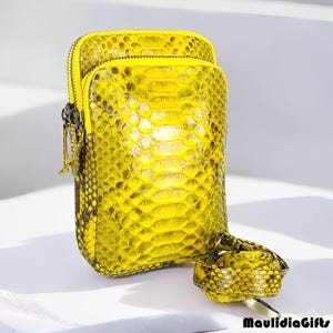 May include: A bright yellow, rectangular crossbody bag with a matching strap. The bag features a textured, snake-skin pattern and a zipper closure. The bag is approximately 7 inches tall and 4 inches wide.