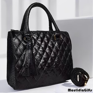 May include: Black quilted handbag with a top handle and a detachable shoulder strap. The bag features a diamond pattern and a decorative tassel. The bag is made of a textured material and has gold-colored hardware.