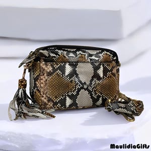 May include: A rectangular snakeskin-patterned crossbody bag with a black zipper and a decorative tassel. The bag features a mix of brown, black, and white tones. A matching key ring is attached. The brand name "MaulidiaGifts" is visible.
