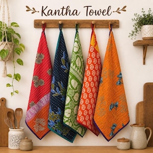 May include: Five rectangular Kantha towels hang from a wooden wall rack. The towels feature vibrant colors including red, navy blue, green, orange, and yellow with intricate floral and geometric patterns, visible stitching, and fabric loops for hanging.