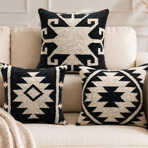 Peut inclure: Trois coussins carrés présentant un motif tissé contrasté noir et crème. Le coussin supérieur affiche un grand motif en étoile, tandis que les deux coussins inférieurs présentent des motifs géométriques en losange et en cercle.