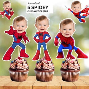Può includere: Cinque decorazioni personalizzate per cupcake con il volto di un bambino su un corpo con costume da Spiderman rosso e blu. Le decorazioni mostrano varie pose d'azione e sono posizionate su cupcake al cioccolato con glassa e sciroppo.