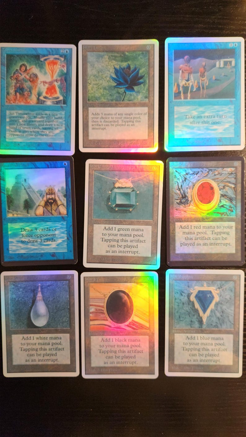 Pu&ograve; includere: Nove carte collezionabili con accenti olografici. Le carte presentano varie illustrazioni fantasy e testo, tra cui un fiore di loto blu, una gemma verde e un globo rosso. Carte per un gioco di carte collezionabili.