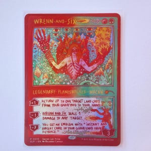 May include: A red Magic: The Gathering card featuring the Planeswalker Wrenn and Six. The card has a detailed illustration of a figure with flames and eyes. Text includes abilities and the card's name.