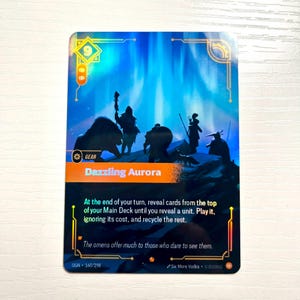 May include: A holographic trading card with a blue and orange design. The card features a silhouette of figures against a backdrop of a glowing aurora borealis. Text on the card reads "Dazzling Aurora" and game instructions.