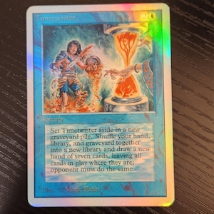 Pu&ograve; includere: Una carta olografica di Magic: The Gathering intitolata "Timetwister". La carta presenta un'illustrazione di una figura e una clessidra infuocata. Il testo descrive la funzione della carta come magia.