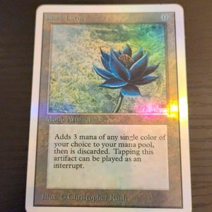 Pu&ograve; includere: Carta collezionabile con un fiore di loto blu. Intitolata "Black Lotus", include testo che descrive la sua funzione nel gioco. La carta ha una finitura olografica.