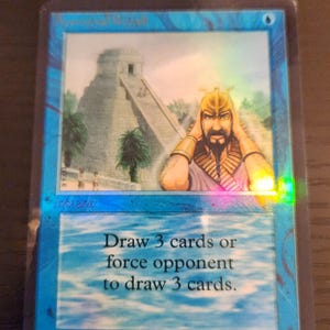 Pu&ograve; includere: Una carta blu di Magic: The Gathering con una scena di tempio e una figura con un elmo d'oro. Il testo della carta recita: "Pesca 3 carte o fai pescare 3 carte all'avversario."