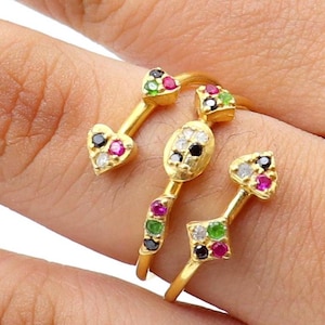 May include: A gold-colored ring with three decorative elements. Each element features colorful gemstones in various shapes, including hearts and diamonds. The ring is designed to wrap around the finger, creating a unique and eye-catching look.