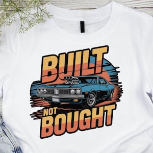 Könnte beinhalten: Weißes T-Shirt mit einer blauen Muscle-Car-Grafik und dem Text "BUILT NOT BOUGHT" in Orange und Gelb. Das Auto hat einen schwarzen Streifen und Chromdetails. Das Design hat einen Retro-Vintage-Stil.
