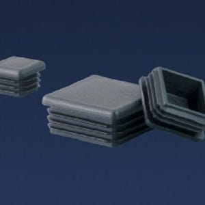 May include: Several dark gray square plastic end caps are displayed against a dark blue background. The caps have a ridged design on the sides, and one cap is shown with its interior exposed. These caps are likely used for furniture or construction.