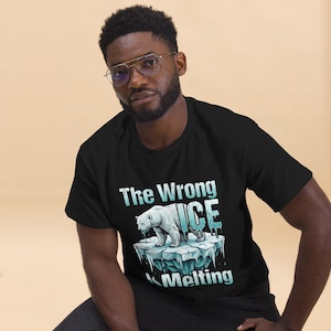 Puede incluir: Camiseta negra con un gráfico de un oso polar sobre un iceberg derritiéndose. El texto dice "The Wrong ICE Melting" en una fuente azul claro. La camiseta la lleva una persona.