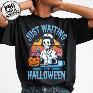 May include: Black t-shirt featuring a Halloween-themed graphic. The design includes a skeleton nurse holding a syringe, a jack-o'-lantern, and the text "JUST WAITING FOR HALLOWEEN" in blue. A sunset backdrop completes the design.