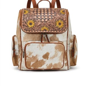 May include: A backpack featuring a white and brown cowhide pattern with a top flap made of brown leather. The flap displays an embossed basket-weave texture, intricate floral scrollwork, and painted yellow sunflowers with dark brown centers.