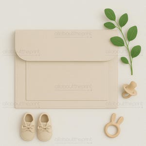 May include: A beige baby essentials flat lay. The image features a beige diaper clutch, a pair of baby shoes, a pacifier, and a wooden bunny-shaped teether. A green leafy branch adds a natural touch to the composition.