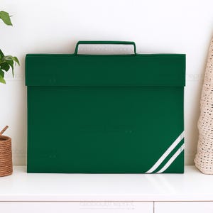 May include: A dark green portfolio with a handle and a white stripe design on the lower right corner. The portfolio is sitting on a white surface.