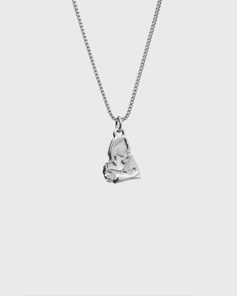 Peut inclure: Un collier argent&eacute; avec un pendentif textur&eacute; de forme abstraite. Le pendentif est suspendu &agrave; une cha&icirc;ne fine. Le collier est pr&eacute;sent&eacute; sur un fond blanc uni.