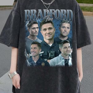 Könnte beinhalten: Dunkelgraues T-Shirt mit einem Grafikdesign eines Mannes, dem Namen "Bradford" und dem Namen "Tim". Das Design enthält mehrere Bilder desselben Mannes. Das T-Shirt hat einen Vintage-Look.