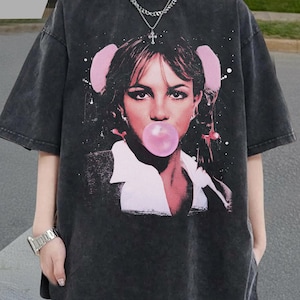 Può includere: T-shirt oversize grigio scuro con una grafica di una donna che soffia una bolla di gomma da masticare. La grafica è nei toni del rosa e del bianco. La maglietta ha maniche corte e un lavaggio vintage.