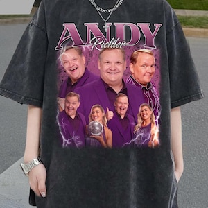 Peut inclure: T-shirt gris foncé avec un graphisme d'Andy Richter et d'autres personnes en costumes violets. Le texte "ANDY Richter" est en rose et violet. Le t-shirt a un aspect vintage et vieilli.