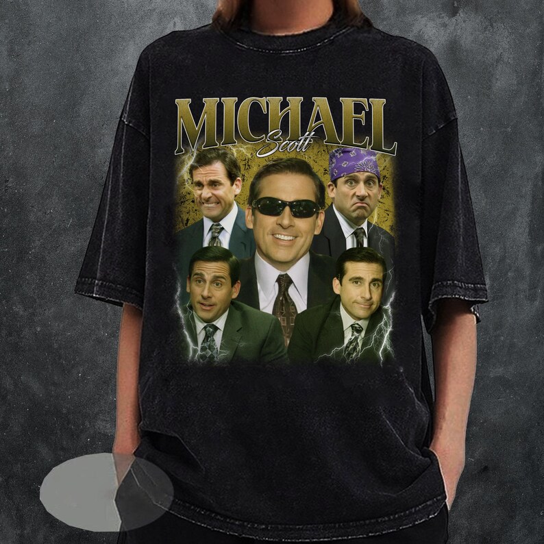 May include: Black t-shirt featuring a collage of images of Michael Scott from The Office, with the name "MICHAEL" in gold lettering. The design includes various expressions and outfits of the character, with lightning bolt accents.