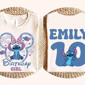 May include: A white t-shirt featuring a blue cartoon character design. The front of the shirt has the text "Birthday Girl" and a character illustration. The back of the shirt has the name "Emily" and the number "10".