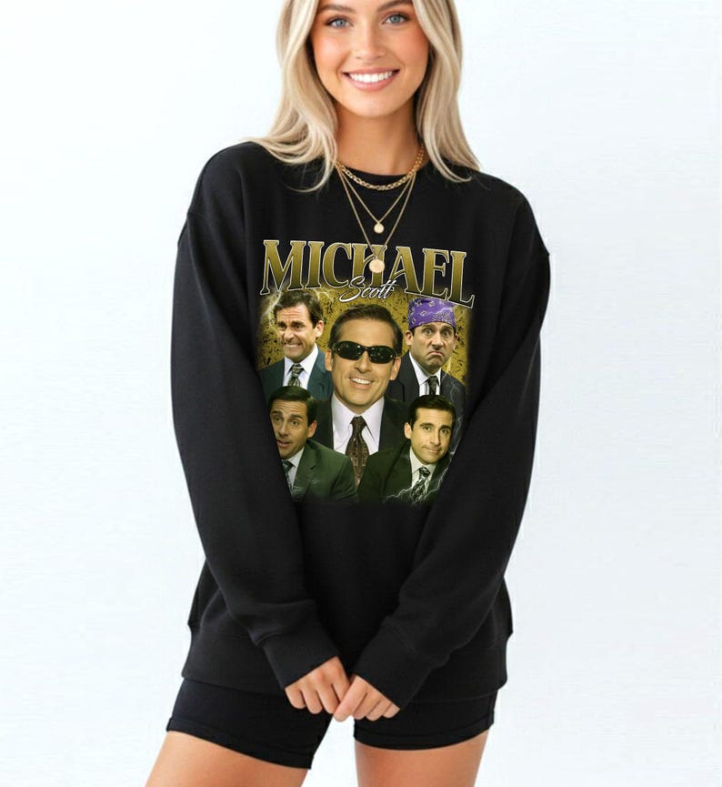 May include: Black sweatshirt featuring a collage of images of Michael Scott, with the name "MICHAEL Scott" in gold lettering. The images show Scott in various expressions and outfits. The sweatshirt is a crew neck style.