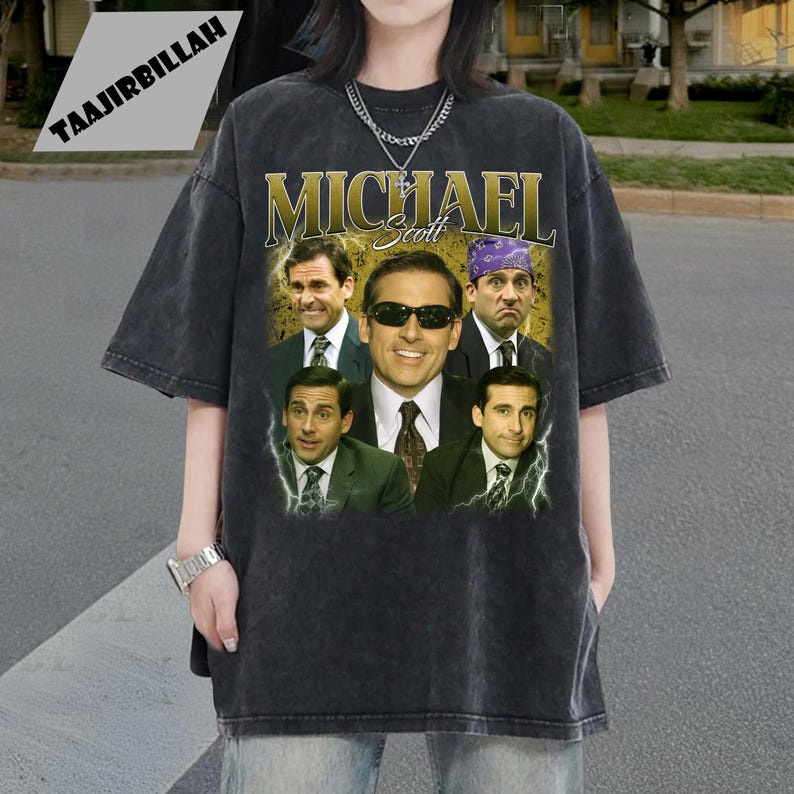 May include: Dark gray t-shirt featuring a collage of images and the name "MICHAEL Scott" in gold lettering. The images are of a man in various poses, some wearing sunglasses and a purple bandana. The shirt has a vintage, distressed look.