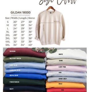 May include: A size chart for a Gildan 18000 unisex sweatshirt, with measurements in inches for sizes S through 5XL. The chart includes width, length, and sleeve measurements. Below the chart are stacks of sweatshirts in various colors.