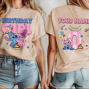 May include: Beige t-shirt with a colorful graphic featuring the words "BIRTHDAY GIRL" and a cartoon character. The back of the shirt has the words "YOUR NAME" and a number 0 with cartoon characters and birthday decorations. The shirt is paired with denim shorts.