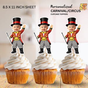 May include: Three cupcakes with circus-themed toppers. Each topper depicts a baby in a red and gold ringmaster outfit, wearing a top hat and holding a cane. The cupcakes are decorated with white frosting. Text on the sheet reads "Personalised Carnival/Circus Cupcake Toppers."