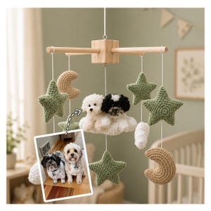 May include: A handmade baby mobile featuring a wooden frame with hanging crochet stars, moons, and a cloud with two small dog figures. The stars are olive green, and the moons are tan. A photo of two dogs is in the lower left corner.