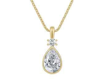 May include: A yellow gold necklace featuring a pear-shaped clear gemstone pendant set in a bezel, accented by a small round clear gemstone above it. The pendant hangs from a delicate yellow gold chain with fine, interlocking oval links.