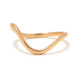 Puede incluir: Un anillo dorado con un diseño ondulado. El anillo es liso y brillante, con la marca "18K" visible. El anillo está sobre un fondo blanco.