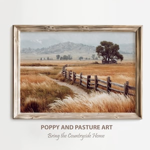 May include: Framed landscape print depicting a rural scene with a wooden fence, a path, and golden grasses. The artwork shows a field with a distant mountain range and a tree near a small building. The text at the bottom reads "POPPY AND PASTURE ART" and "Bring the Countryside Home."