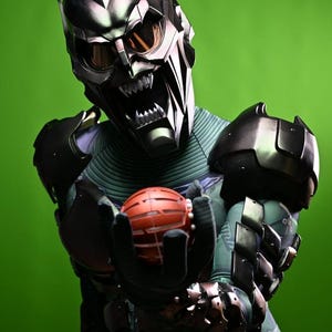 May include: A detailed image of a Green Goblin costume. The mask is metallic with sharp angles and menacing teeth. The costume features armored elements and a red, spherical grenade held in gloved hands. The background is a solid green.