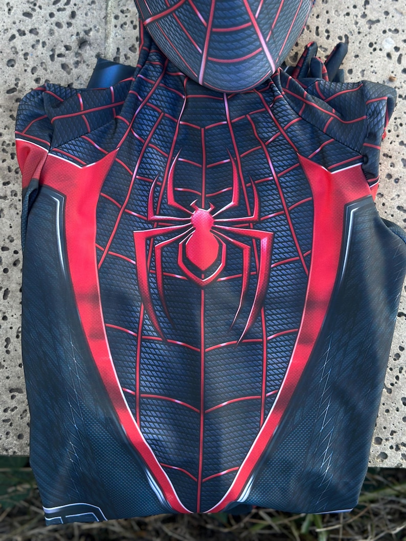 May include: A black and red Spider-Man costume with a hood. The costume features a spider web design with a large spider emblem on the chest. Red accents outline the design, creating a striking visual.