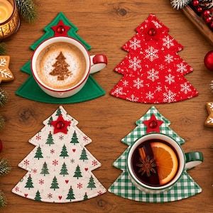 Könnte beinhalten: Vier weihnachtsbaumförmige Stoffuntersetzer mit verschiedenen Mustern: ein einfarbig grüner, ein roter mit weißen Schneeflocken, ein cremefarbener mit grünen Bäumen und roten Herzen sowie ein grün-weiß karierter.
