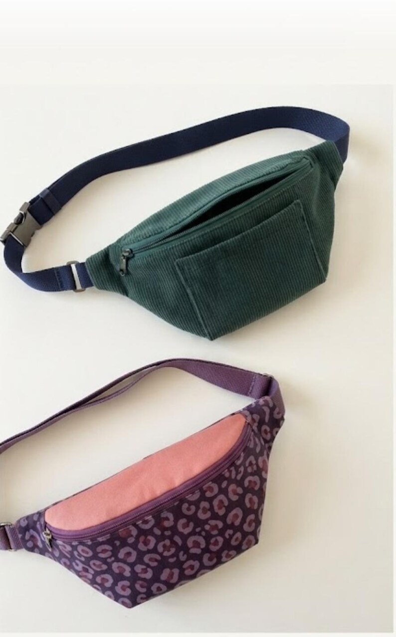 May include: Two bum bags. One is dark green corduroy with a navy blue adjustable strap and a front zipper pocket. The second bum bag features a purple leopard print pattern with a solid pink top panel, a purple zipper, and a purple strap.