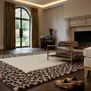 May include: A living room featuring a large area rug with a cream-colored center and a leopard print border. The room includes a fireplace, a sofa, a coffee table, and a large mirror. The rug adds a touch of luxury to the space.