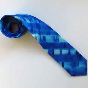 May include: A blue silk tie with a white and blue abstract pattern.