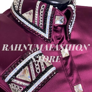 May include: A close-up of a burgundy satin shirt with elaborate embellishments. The collar and cuffs are adorned with silver chains, black and white accents, and large, clear crystals. The text "RAHNUMAFASHION STORE" is visible.