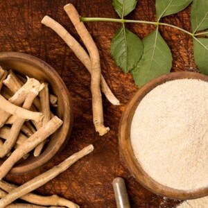 K&ouml;nnte beinhalten: Draufsicht auf Ashwagandha-Produkte. Zwei Holzschalen enthalten Ashwagandha-Wurzelst&uuml;cke und -Pulver. Kapseln, Bl&auml;tter und Wurzelst&uuml;cke sind auf einer Holzoberfl&auml;che verstreut.